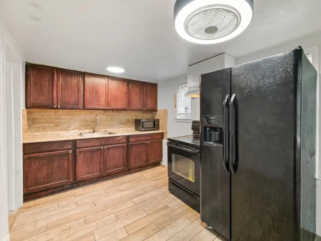 a kitchen with a refrigerator a sink and wooden floor