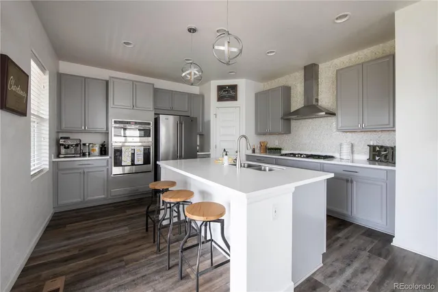 a view of kitchen with stainless steel appliances granite countertop a stove top oven a sink a refrigerator cabinets and wooden floor