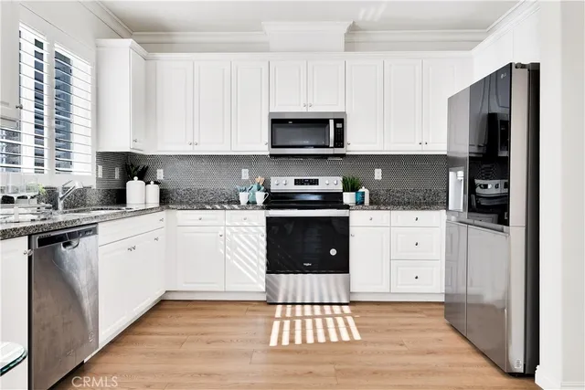 a kitchen with granite countertop a stove a sink and white cabinets