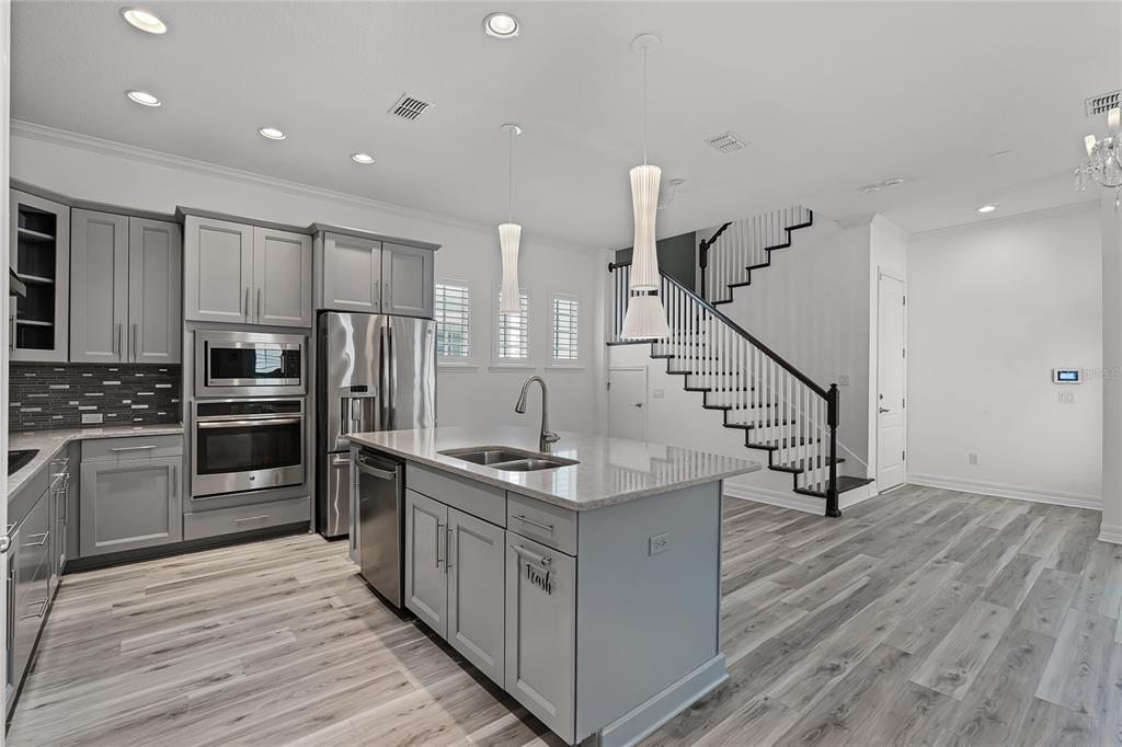 1515 Resolute Street Celebration, FL 34747 - Photo 11 of 56 a kitchen with stainless steel appliances kitchen island granite countertop a wooden floor a stove a sink and a refrigerator