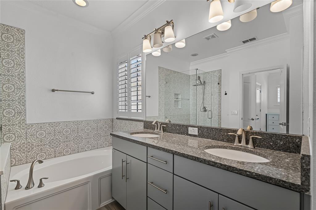 1515 Resolute Street Celebration, FL 34747 - Photo 35 of 56 a bathroom with a granite countertop sink a large mirror a bathtub and window