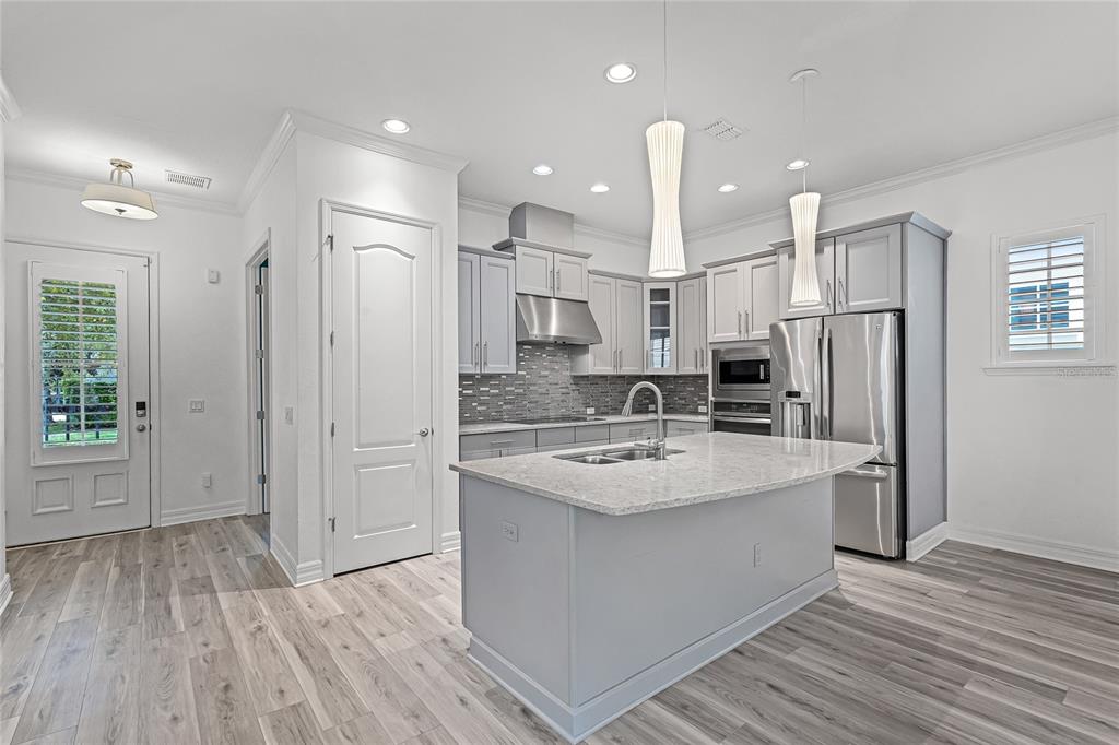 1515 Resolute Street Celebration, FL 34747 - Photo 8 of 56 a large kitchen with stainless steel appliances granite countertop a large center island a stove a refrigerator white cabinets and wooden floor