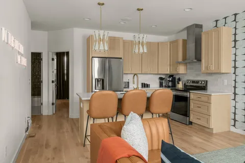 a kitchen with stainless steel appliances granite countertop a refrigerator a sink dishwasher a stove and white cabinets with wooden floor