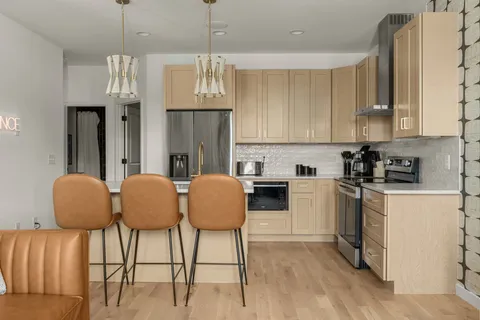 a kitchen with stainless steel appliances granite countertop a stove top oven a refrigerator a sink and a dining table with wooden floor