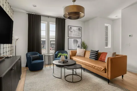 a living room with furniture a ceiling fan and a flat screen tv