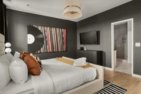 a bedroom with a bed and a flat tv screen on dresser