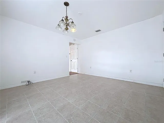 an empty room with a chandelier fan and glass door