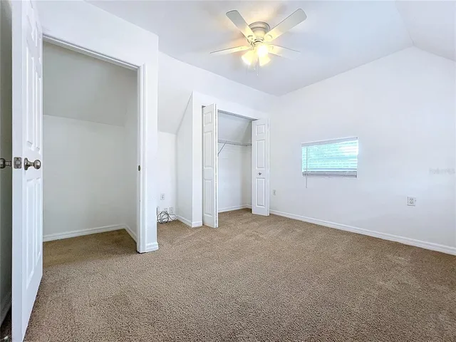 an empty room with a fan & a window