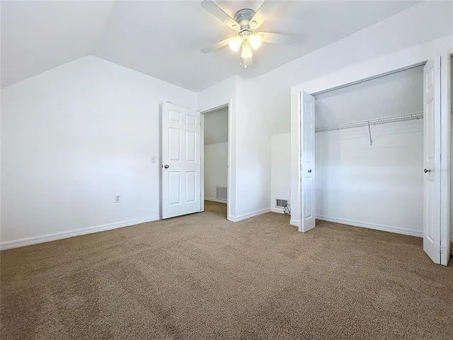 an empty room with closet and a chandelier fan