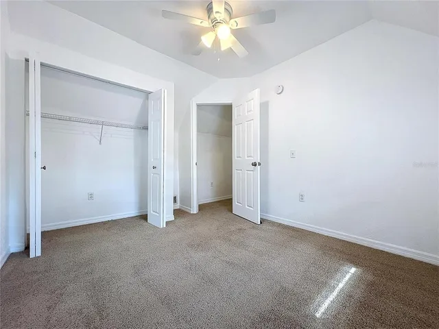 an empty room with closet and a chandelier fan