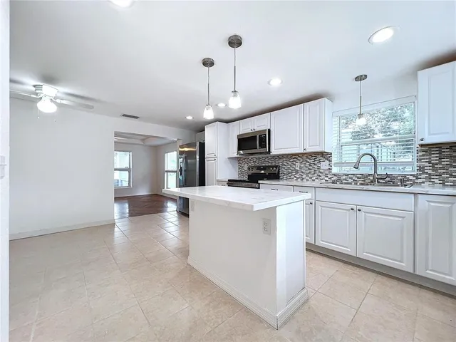 a kitchen with kitchen island granite countertop a sink a counter space appliances and cabinets