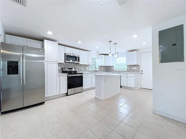 a large kitchen with a large counter top stainless steel appliances and cabinets
