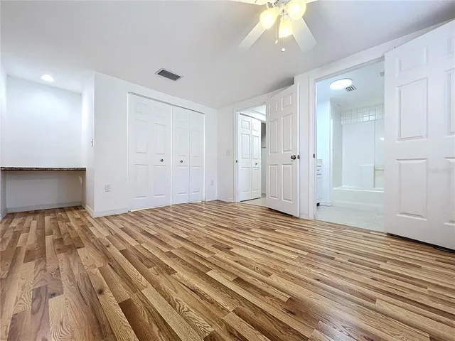 a view of empty room with wooden floor and fan