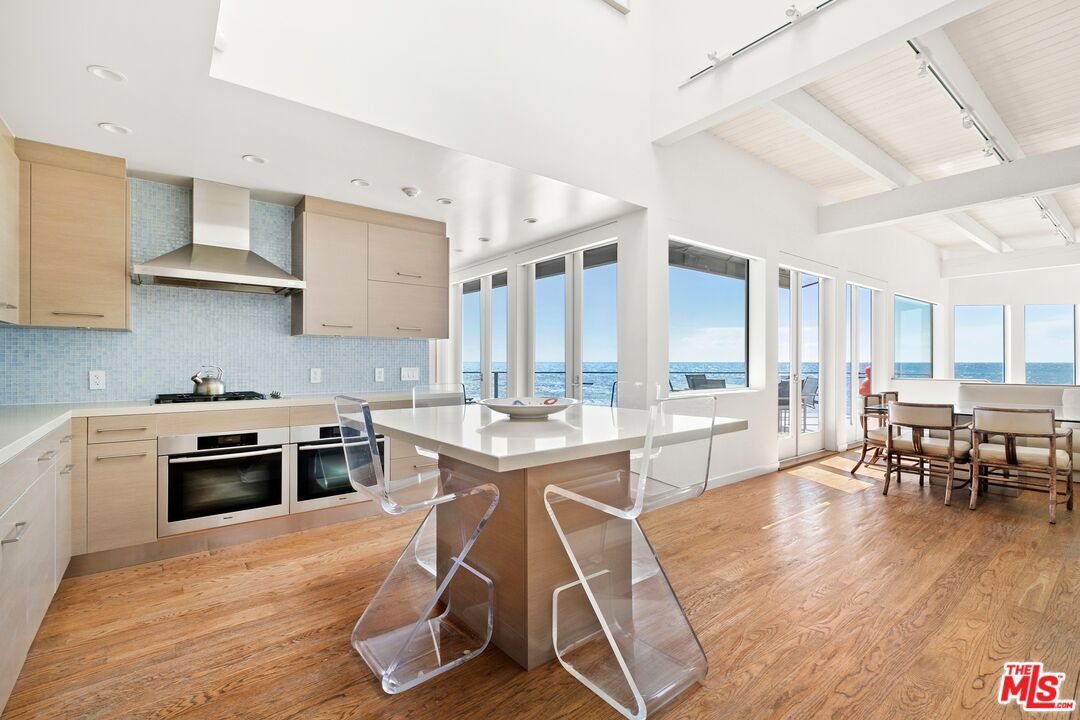 24254 Malibu Road Malibu, CA 90265 - Photo 6 of 26 a kitchen with stainless steel appliances a stove a sink dishwasher a stove and a dining table with wooden floor