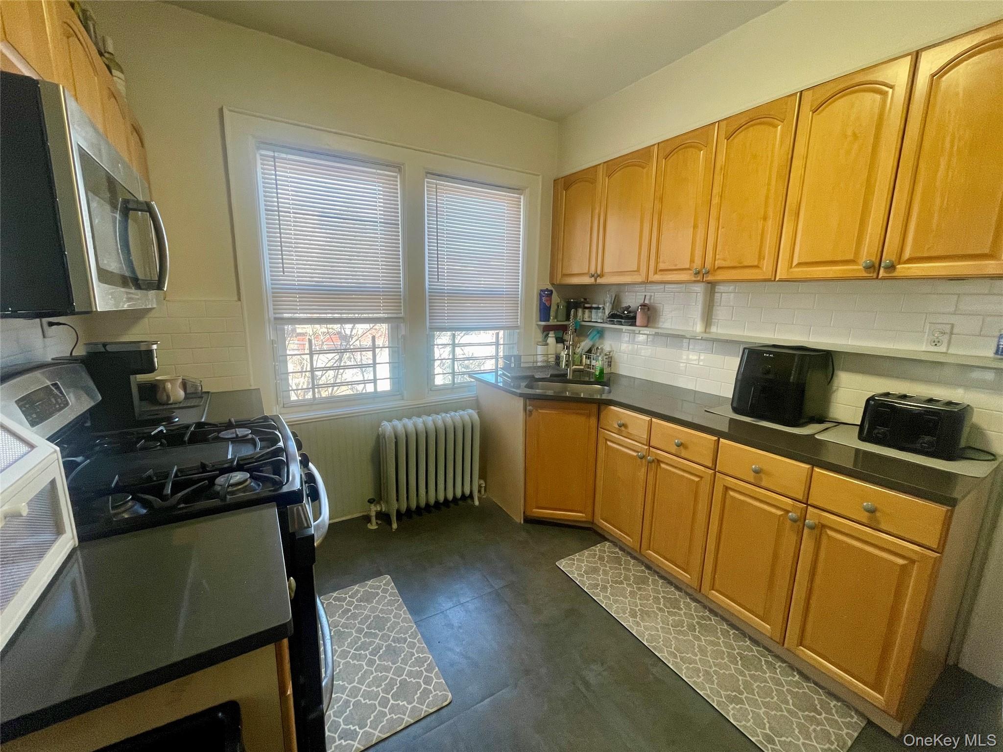 372 East 235th Street Bronx, NY 10470 - Photo 14 of 36 a kitchen with a sink a stove and cabinets