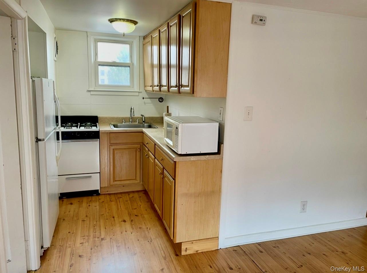372 East 235th Street Bronx, NY 10470 - Photo 25 of 36 a kitchen with a sink a stove wooden floor and cabinets