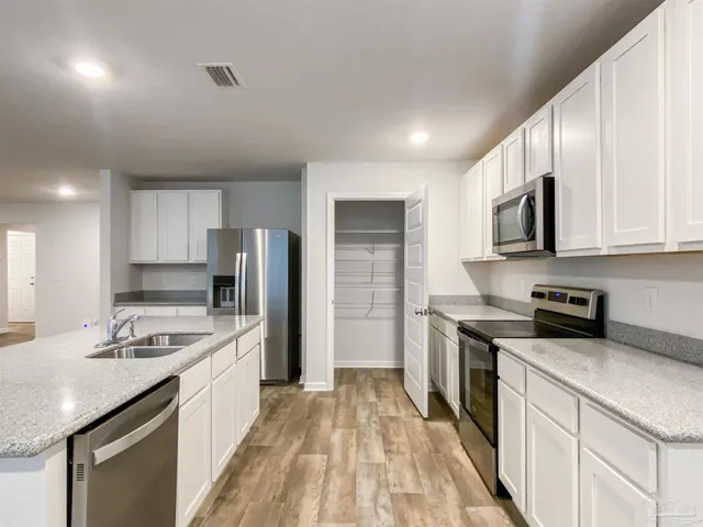 a kitchen with stainless steel appliances granite countertop a sink stove microwave and refrigerator