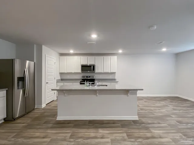 a large kitchen with kitchen island a large counter top and stainless steel appliances