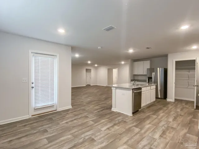 a large white kitchen with kitchen island a sink stainless steel appliances and cabinets