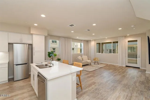 a kitchen with stainless steel appliances kitchen island granite countertop a refrigerator and a stove top oven