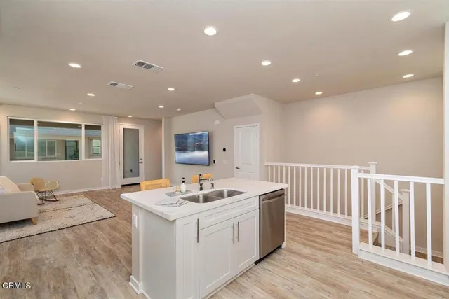 a open kitchen with kitchen island a sink appliances and a large window