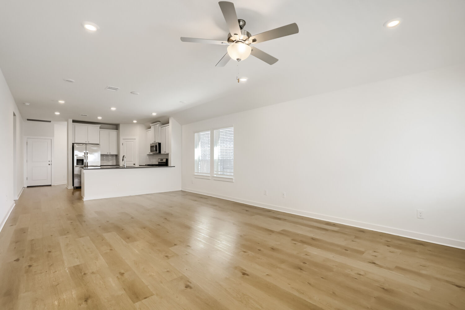 356 Brandywine Road Hutto, TX 78634 - Photo 3 of 11 Blonde hardwood flooring stretches across an open-concept living space with a modern kitchen.