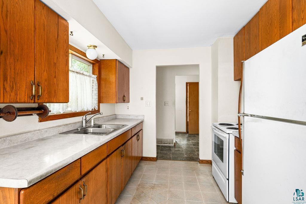 4930 Oneida Street Duluth, MN 55804 - Photo 7 of 19 Kitchen with white appliances, sink, and light tile patterned flooring