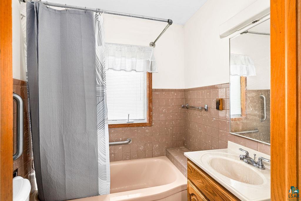 4930 Oneida Street Duluth, MN 55804 - Photo 10 of 19 Bathroom with tile walls, toilet, vanity, and decorative backsplash