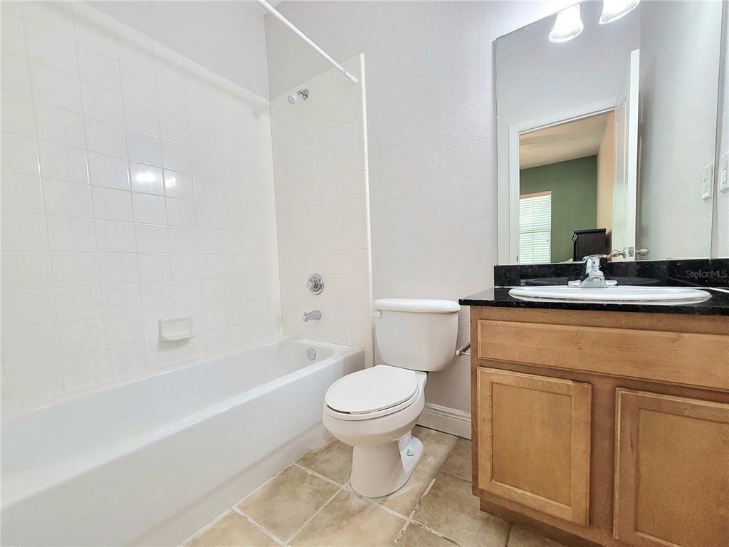 2946 Southwest 35th Place, Unit 44 Gainesville, FL 32608 - Photo 25 of 25 a bathroom with a granite countertop sink a toilet a mirror and bathtub