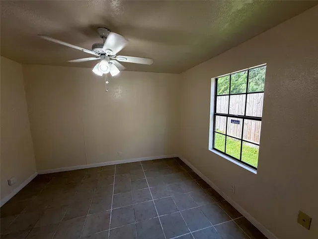 en empty room with windows and ceiling fan