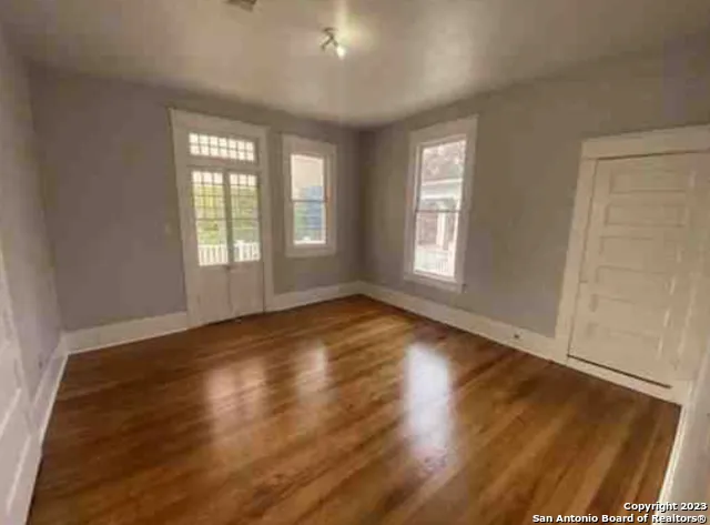 an empty room with wooden floor and windows