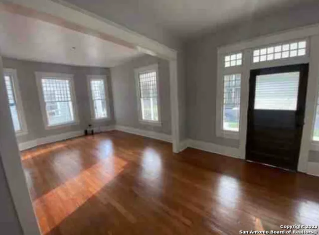 an empty room with wooden floor and windows