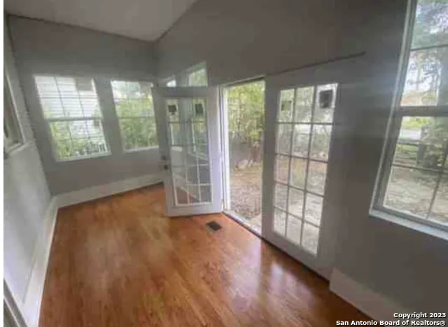 a view of an empty room with wooden floor and a window