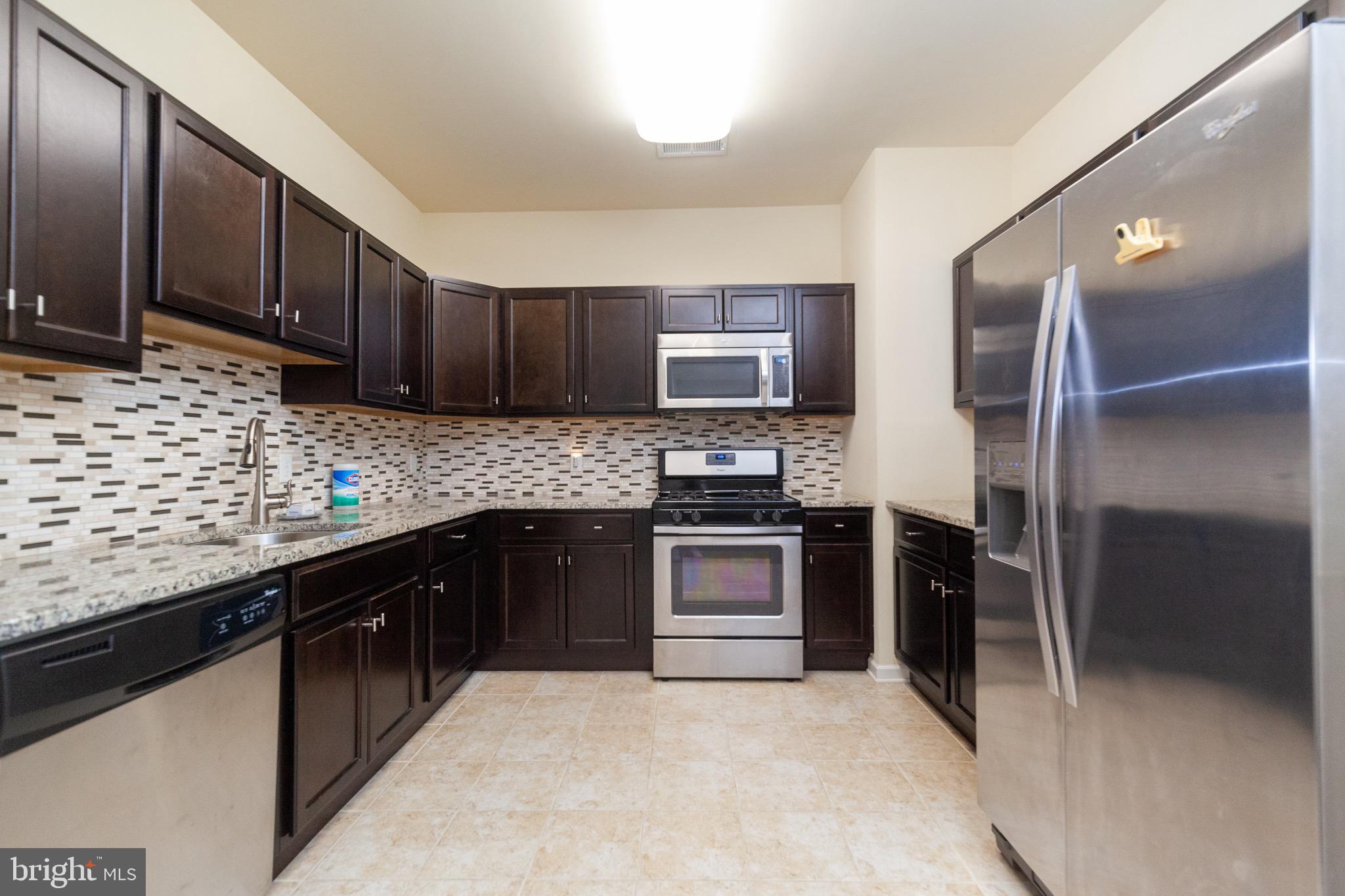4514 Champions Run, Unit 4514 Cherry Hill, NJ 08002 - Photo 5 of 16 a kitchen with stainless steel appliances granite countertop a stove refrigerator and cabinets