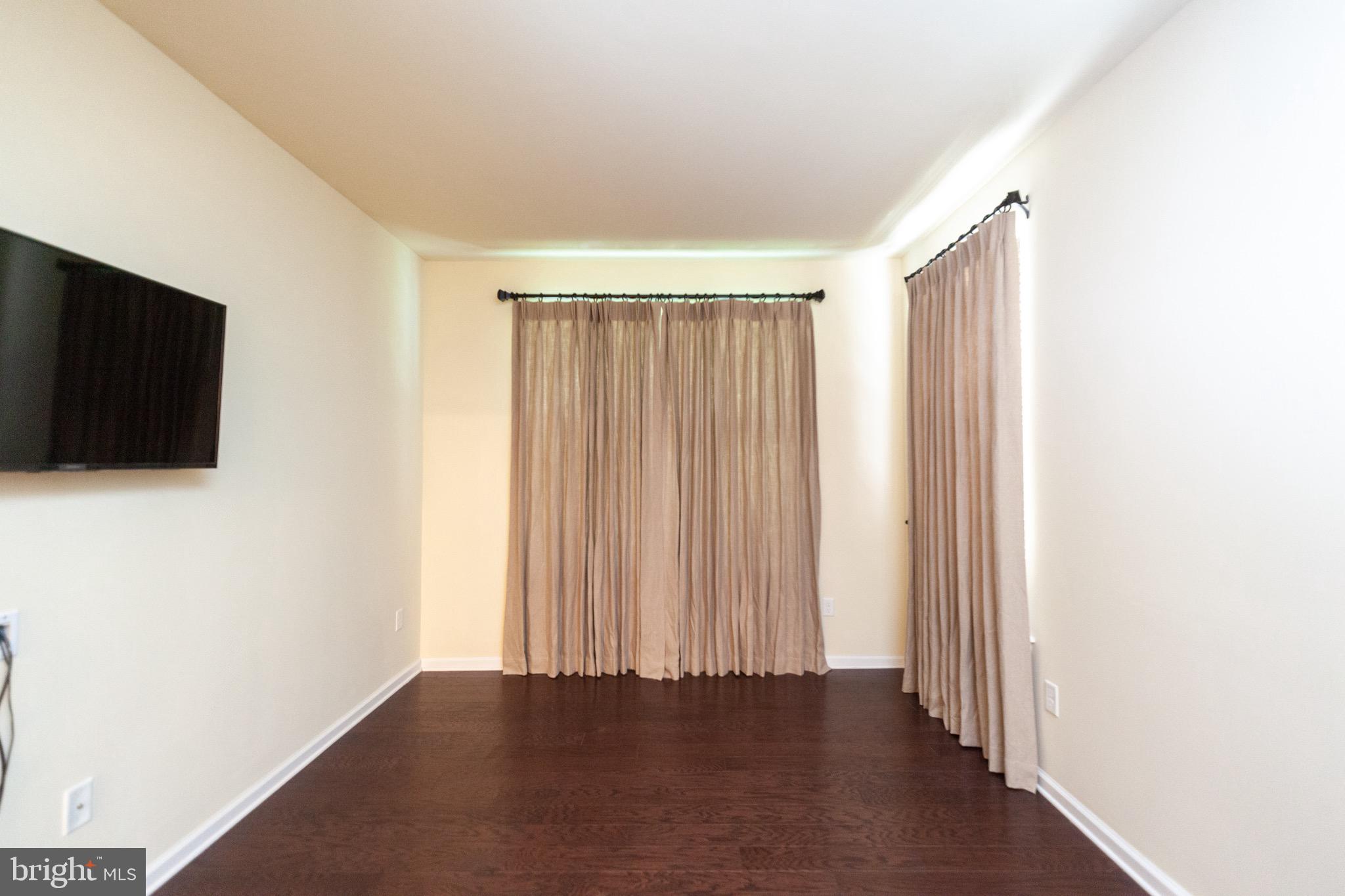 4514 Champions Run, Unit 4514 Cherry Hill, NJ 08002 - Photo 10 of 16 a view of an empty room with wooden floor and a flat screen tv