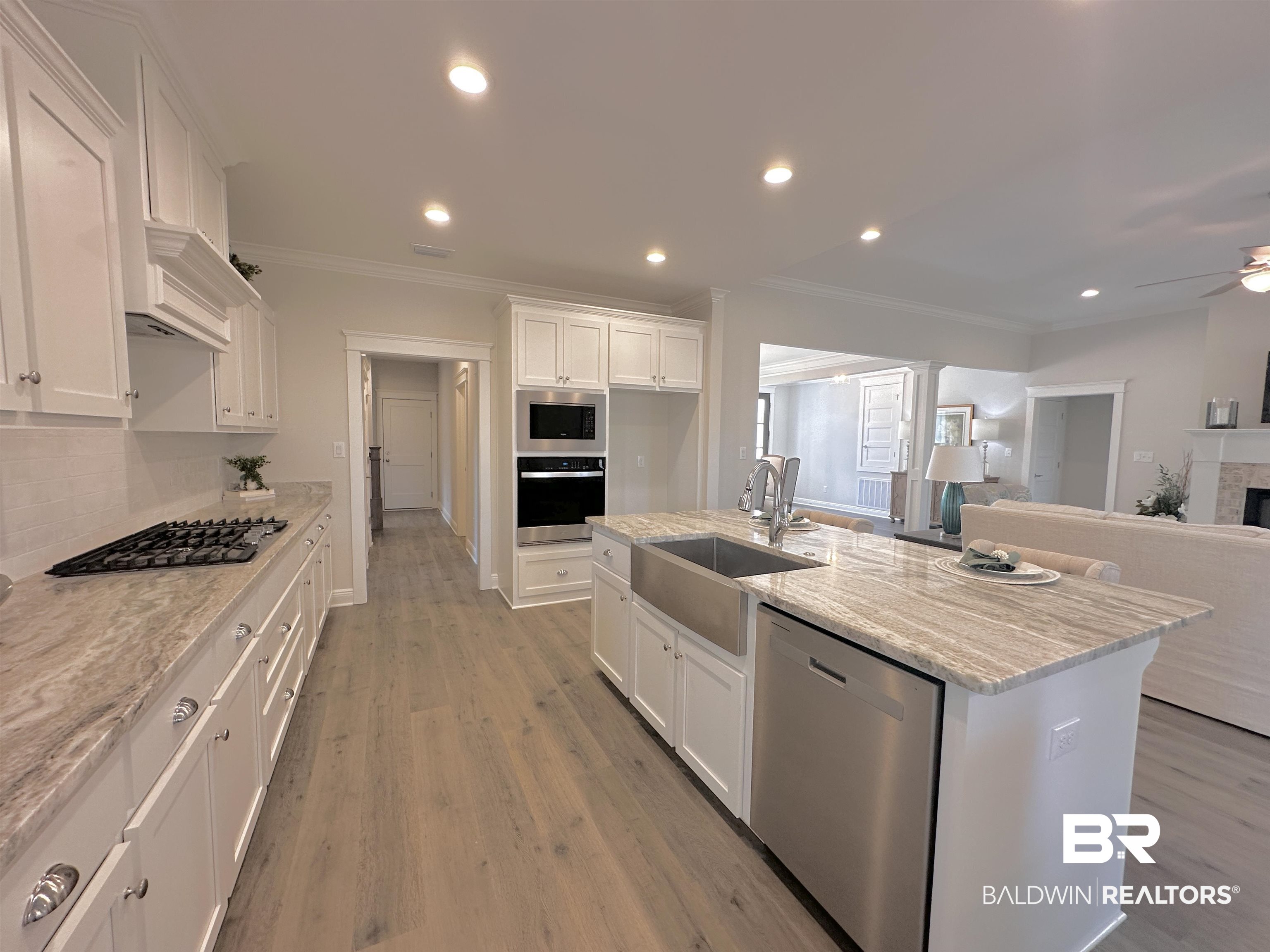 691 Kitfox Avenue Fairhope, AL 36532 - Photo 7 of 42 Kitchen featuring sink, appliances with stainless steel finishes, light stone countertops, a kitchen island with sink, and white cabinets