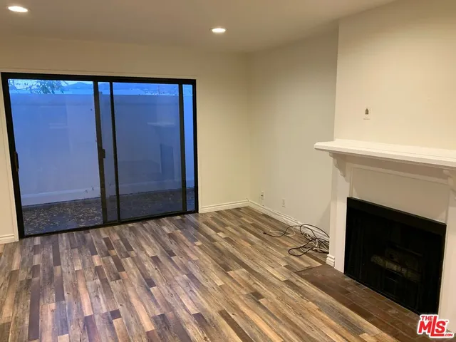a view of empty room with wooden floor and fireplace