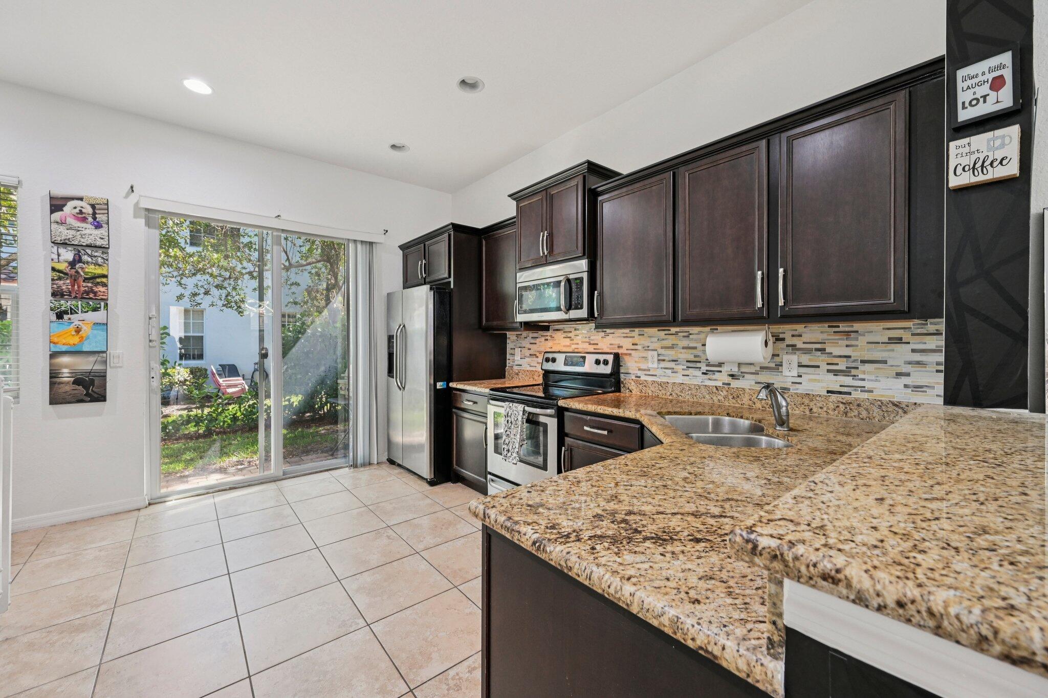 482 Graham Place Boynton Beach, FL 33435 - Photo 7 of 39 a kitchen with granite countertop a stove a sink and a microwave