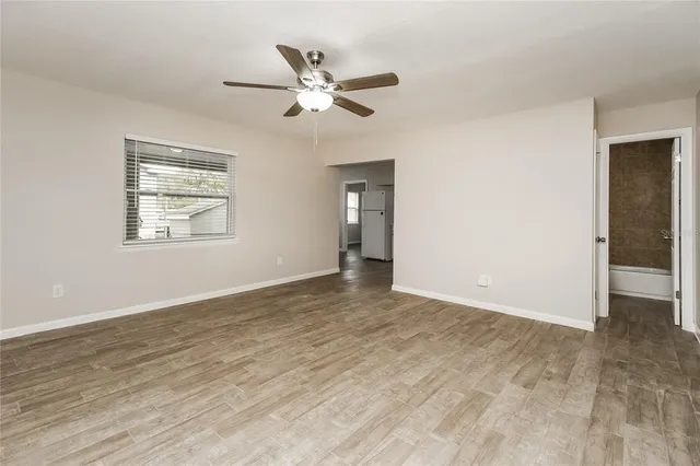 a view of an empty room with wooden floor and a window