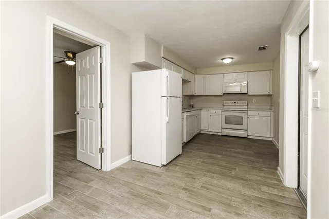 a view of a kitchen with refrigerator and white cabinets