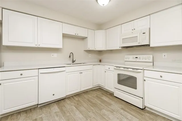 a white kitchen with granite countertop white cabinets and white appliances