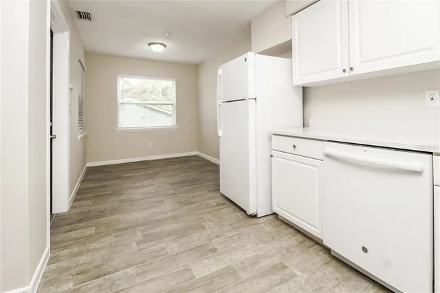 a view of a kitchen with refrigerator and white cabinets