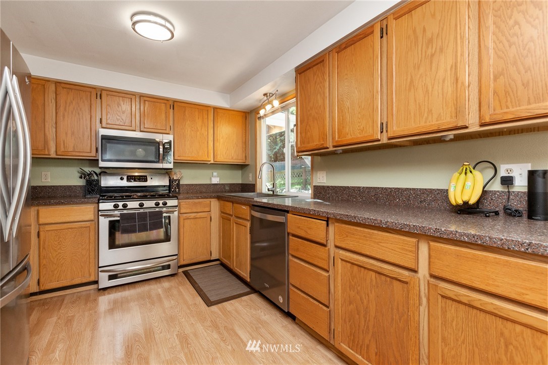 21814 4th Avenue Southeast Bothell, WA 98021 - Photo 9 of 25 a kitchen with granite countertop wooden cabinets and a stove top oven