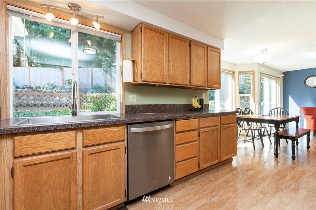 21814 4th Avenue Southeast Bothell, WA 98021 - Photo 10 of 25 a kitchen with granite countertop a stove a sink and white cabinets with wooden floor