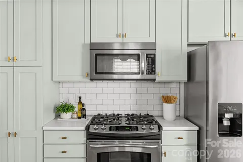 a kitchen with stainless steel appliances a stove and white cabinets