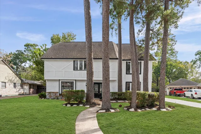 a front view of a house with a garden and tree