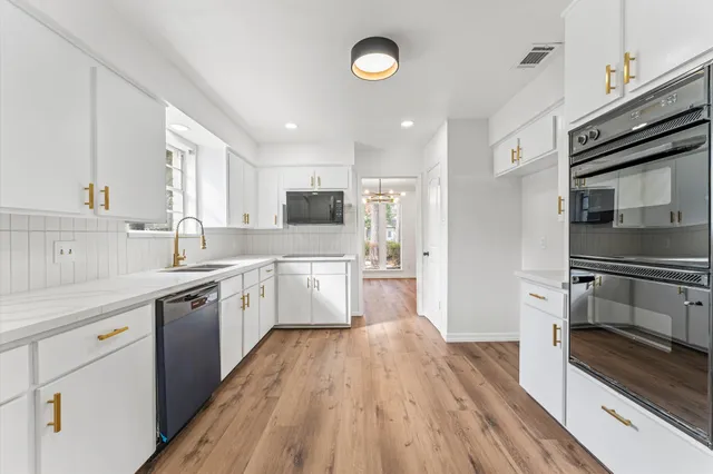a large kitchen with cabinets wooden floor and stainless steel appliances