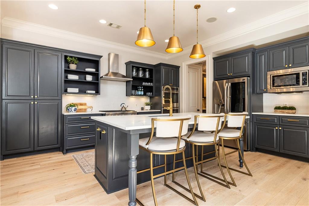 6810 Lullwater Road Cumming, GA 30040 - Photo 20 of 63 a kitchen with stainless steel appliances granite countertop a stove top oven a refrigerator a sink and a dining table with chairs