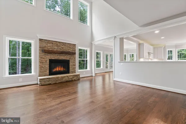 a view of an empty room with wooden floor fireplace and a window