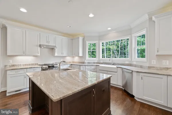 a kitchen with kitchen island a sink stainless steel appliances and white cabinets